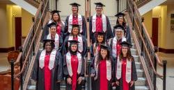 Group of 11 adult students in regalia taking a group photo at a graduation senior send-off celebration.