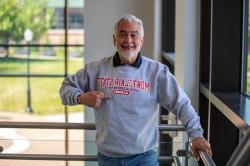 Adult degree completion student proudly wears a Montclair State University alumni crewneck sweatshirt on campus.